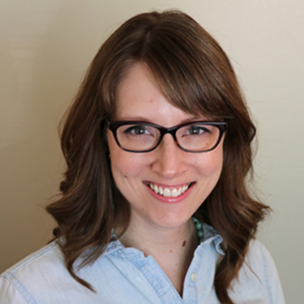 sarah witry, a white woman with brown hair, wearing a blue shirt and glasses