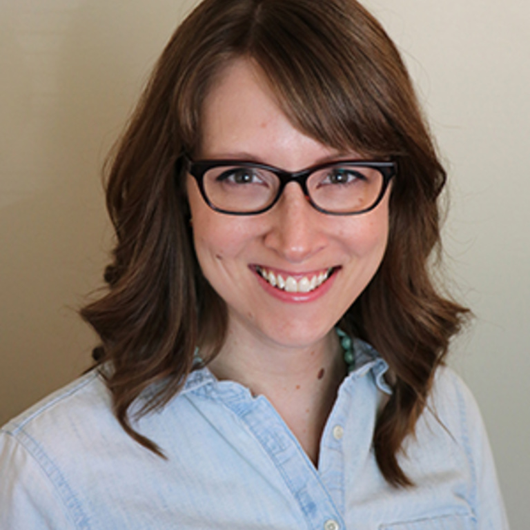 sarah witry, a white woman with brown hair, wearing a blue shirt and glasses