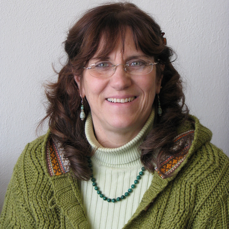 Yvonne Farley, a white woman with brown hair and glasses wearing a green sweater