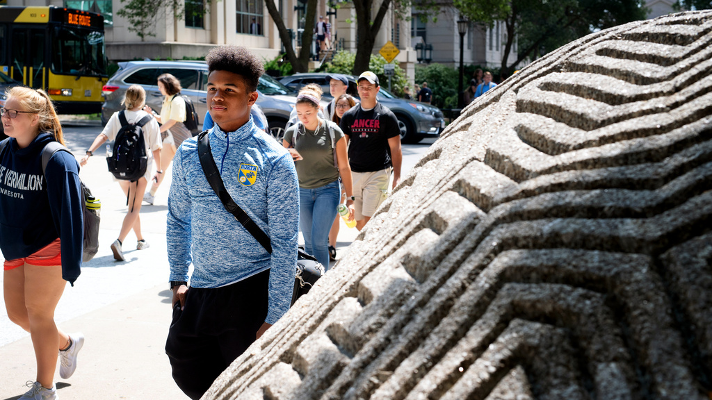 Students walking by the rock brain statue on the T. Anne Cleary Walkway.