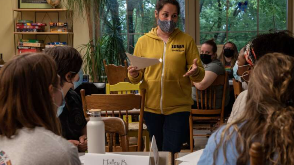 Kara Houser wearing a yellow sweatshirt, teaching a class of social work students in Wild Bill's